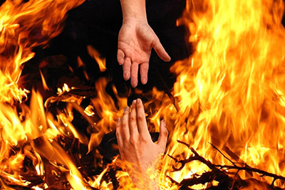 Hand reaching for help from flames 
